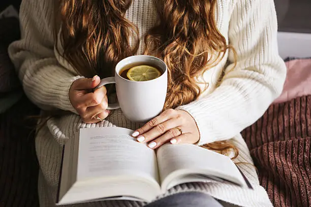 Adult relaxing with a book and tea